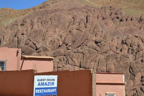 a rock mountain with a sign in front of a building at Maison D'hote Amazir in Boumalne