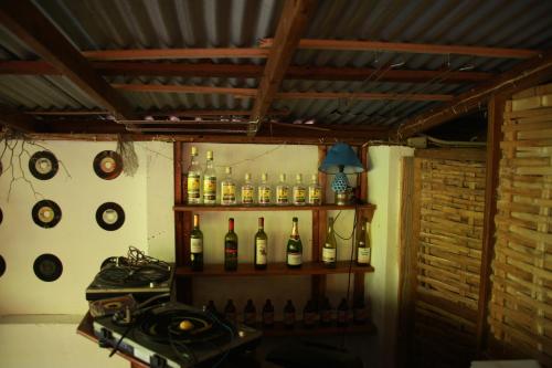 a shelf with bottles of wine and clocks on the wall at La Familia Guest House and Natural Farm in Port Antonio