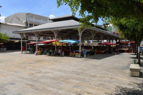 een openluchtmarkt met een paviljoen met tafels en parasols bij KAZA CHARLY F2 in Les Abymes