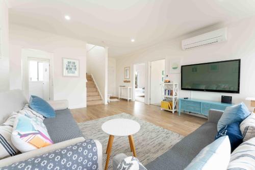 a living room with a couch and a flat screen tv at Boomer Beach Retreat- Pet and Family Friendly in Port Elliot