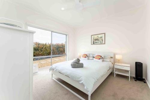 Dormitorio blanco con cama y ventana grande en Boomer Beach Retreat- Pet and Family Friendly, en Port Elliot