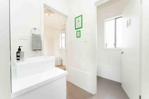 a white bathroom with a sink and a shower at Boomer Beach Retreat- Pet and Family Friendly in Port Elliot