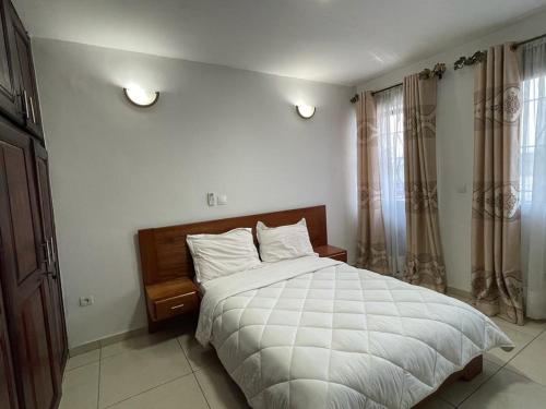 a bedroom with a large white bed and windows at Résidence 2JGE in Douala