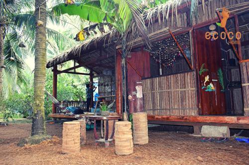 Cabaña pequeña con mesa y palmera en Ecoco Homestay Mekong, en Ben Tre