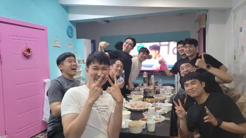 a group of people sitting around a table with food at Jeju Vision House in Jeju