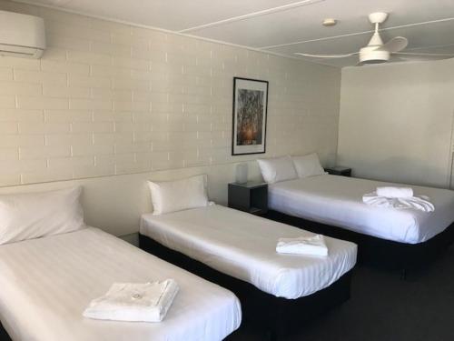 una camera con tre letti con lenzuola bianche di Vineland Motel Mildura a Mildura