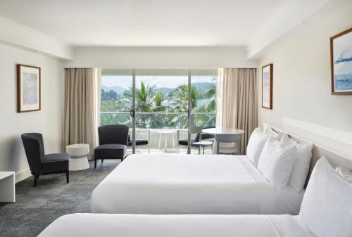 ハミルトン島にあるリーフ ビュー ホテルのベッド、テーブル、椅子が備わるホテルルームです。