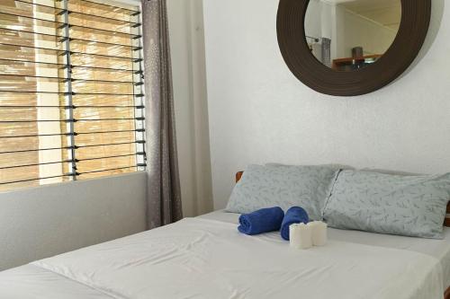 ein Bett mit zwei blauen Kissen und einem Spiegel in der Unterkunft The balcony of the camiguin island in Mambajao