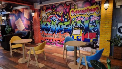 een kamer met tafels en stoelen en een muur met graffiti bij Khaosan Art Hotel - SHA Plus Certified in Bangkok