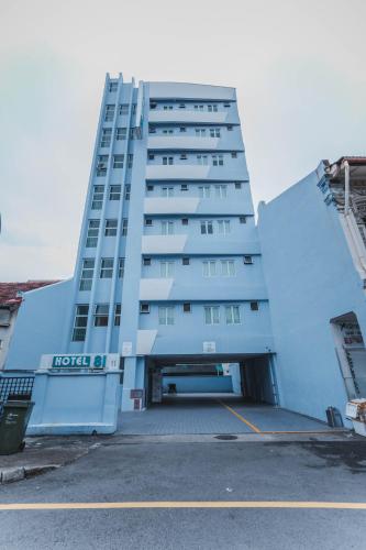 a tall white building with a parking lot at Hotel 81 Joy in Singapore