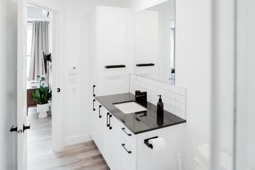 a white bathroom with a black counter in it at CONDO MID-CENTURY MODERN STYLE - POOL/TERRACE in Quebec City
