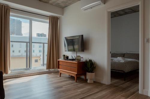 um quarto com uma cama, uma televisão e uma janela em CONDO MID-CENTURY MODERN STYLE - POOL/TERRACE em Cidade de Quebec