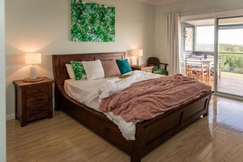- une chambre avec un grand lit et une table avec une lampe dans l'établissement Aldinga Bay Bungalow Ocean View Retreat, à Sellicks Beach