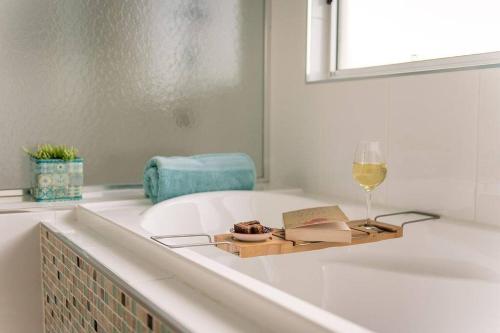une baignoire avec un verre de vin et un livre dans l'établissement Aldinga Bay Bungalow Ocean View Retreat, à Sellicks Beach