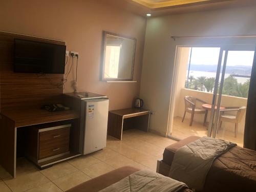 a bedroom with a bed and a television and a balcony at Al Deyafa Hotel in Aqaba