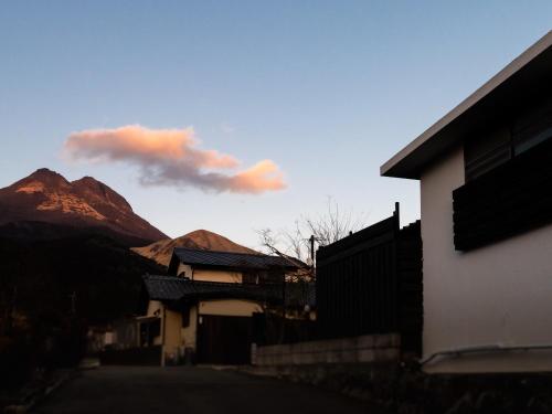 a building with mountains in the background with a sky at Yufuin Wasaku in Yufuin