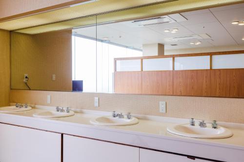 a bathroom with three sinks and a large mirror at KAMENOI HOTEL Itako in Itako