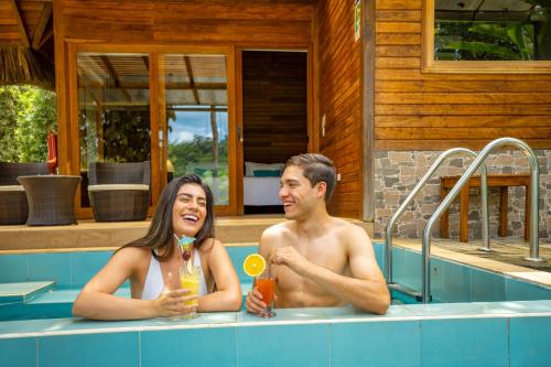 a man and a woman sitting in a swimming pool at El Jardin Lodge & Spa in Puerto Misahuallí