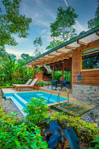 a house with a swimming pool in a garden at El Jardin Lodge & Spa in Puerto Misahuallí