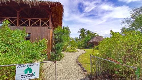 a walk way to a building with a sign at Moalboal Eco Lodge in Moalboal