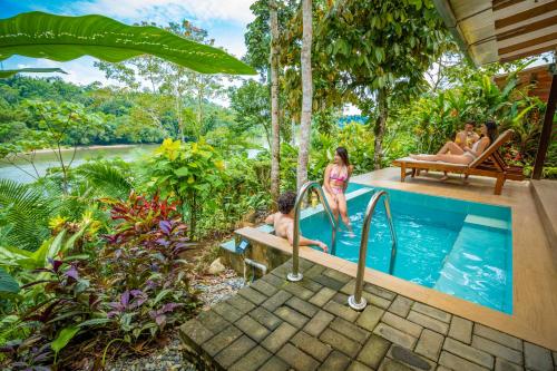 a group of people sitting around a pool in a resort at El Jardin Lodge & Spa in Puerto Misahuallí