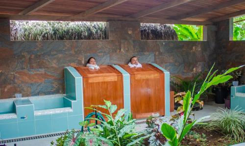 two people are sitting in a tub in a garden at El Jardin Lodge & Spa in Puerto Misahuallí