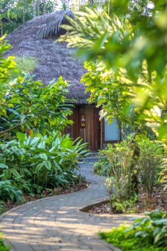 a pathway leading to a thatch roofed building at El Jardin Lodge & Spa in Puerto Misahuallí