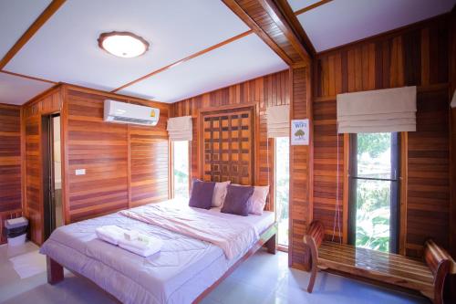 um quarto com uma cama num quarto com paredes de madeira em Romyen House em Ban Nong Nam Khan