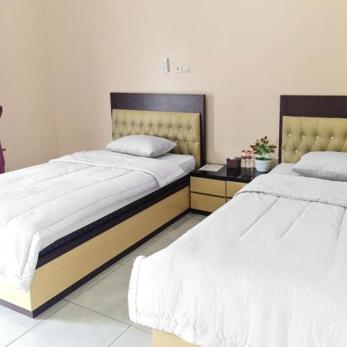 dos camas sentadas una al lado de la otra en un dormitorio en RedDoorz @ Jalan Nyai Enat Sampit en Sampit