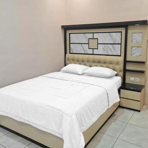 um quarto com uma cama com lençóis brancos e uma janela em RedDoorz @ Jalan Nyai Enat Sampit em Sampit