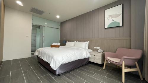 1 dormitorio con 1 cama grande y 1 silla rosa en Twelve Constellation Garden Resort, en Hengchun