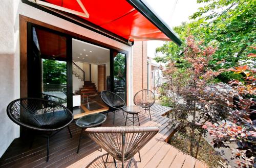 eine Terrasse mit Stühlen, Tischen und einem Sonnenschirm in der Unterkunft 暖炉之宿 コンセプトハウス星田 in Katano