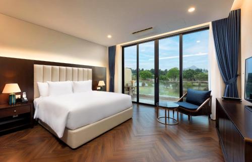 a bedroom with a white bed and a large window at Wyndham Sky Lake Resort and Villas in Hanoi