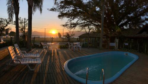 a hot tub on a deck with a sunset in the background at Pousada Canoa Azul na Praia da Ferrugem in Garopaba