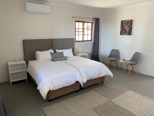 a bedroom with a large white bed and a window at Otjibamba Lodge in Otjiwarongo