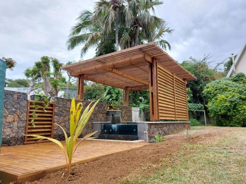 a wooden deck with a barbecue grill in a backyard at La Rose du Sud in Saint-Joseph
