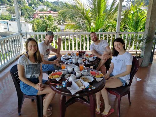 eine Gruppe von Menschen, die an einem Tisch mit Essen sitzen in der Unterkunft Kandy City Village in Kandy