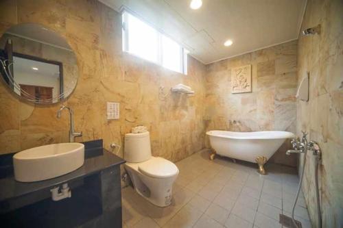 a bathroom with a tub and a toilet and a sink at Green Shine B&B in Nanzhuang