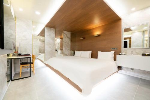 a bedroom with a large white bed and a bathroom at Ytt Hotel in Busan