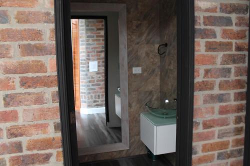 a bathroom with a mirror and a brick wall at Villa La F in Guasca