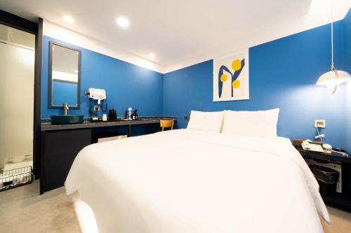a bedroom with a large white bed and a blue wall at Ytt Hotel in Busan