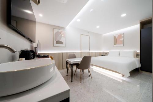 - une chambre avec un lit, un bureau et un lavabo dans l'établissement Ytt Hotel, à Busan