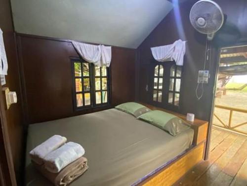 a bedroom with a bed with two towels and a fan at Pinks Bungalow in Baan Tai
