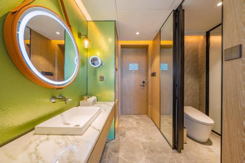 a bathroom with a sink and a mirror and a toilet at Holiday Inn Zhuhai City Center by IHG in Zhuhai