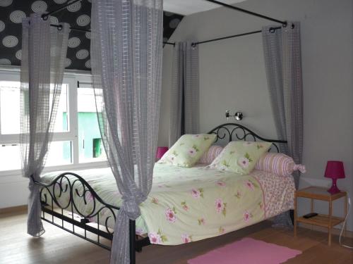 ein Schlafzimmer mit einem Bett mit Baldachin und rosa Kissen in der Unterkunft La Grange de David is accessible to people with reduced mobility 