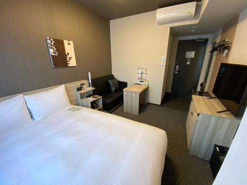 a bedroom with a large bed and a living room at Hotel Route Inn Shunan - Tokuyama Higashi Inter - in Shunan