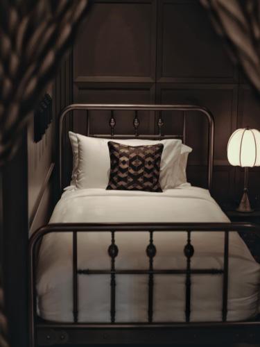 a bed with a metal frame and pillows and two lamps at Hotel Verdigris in Phuket Town