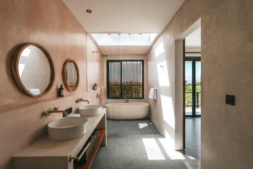 a bathroom with two sinks and a tub and a mirror at Botanique Villa & Studio in Tanah Lot