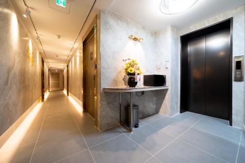 a hallway with a table and a black door at Ytt Hotel in Busan