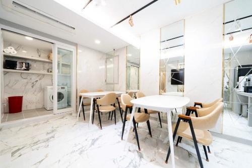 a dining room with white marble floors and tables and chairs at Ytt Hotel in Busan
